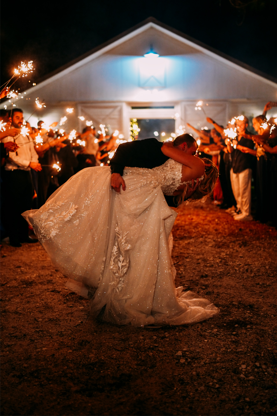 Groom dipping the bride as guests cheer at Ever After Farms Ranch wedding reception